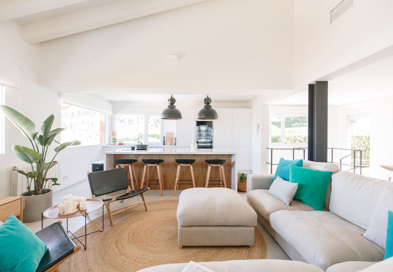 Living-dining room with open kitchen, garden and pool views